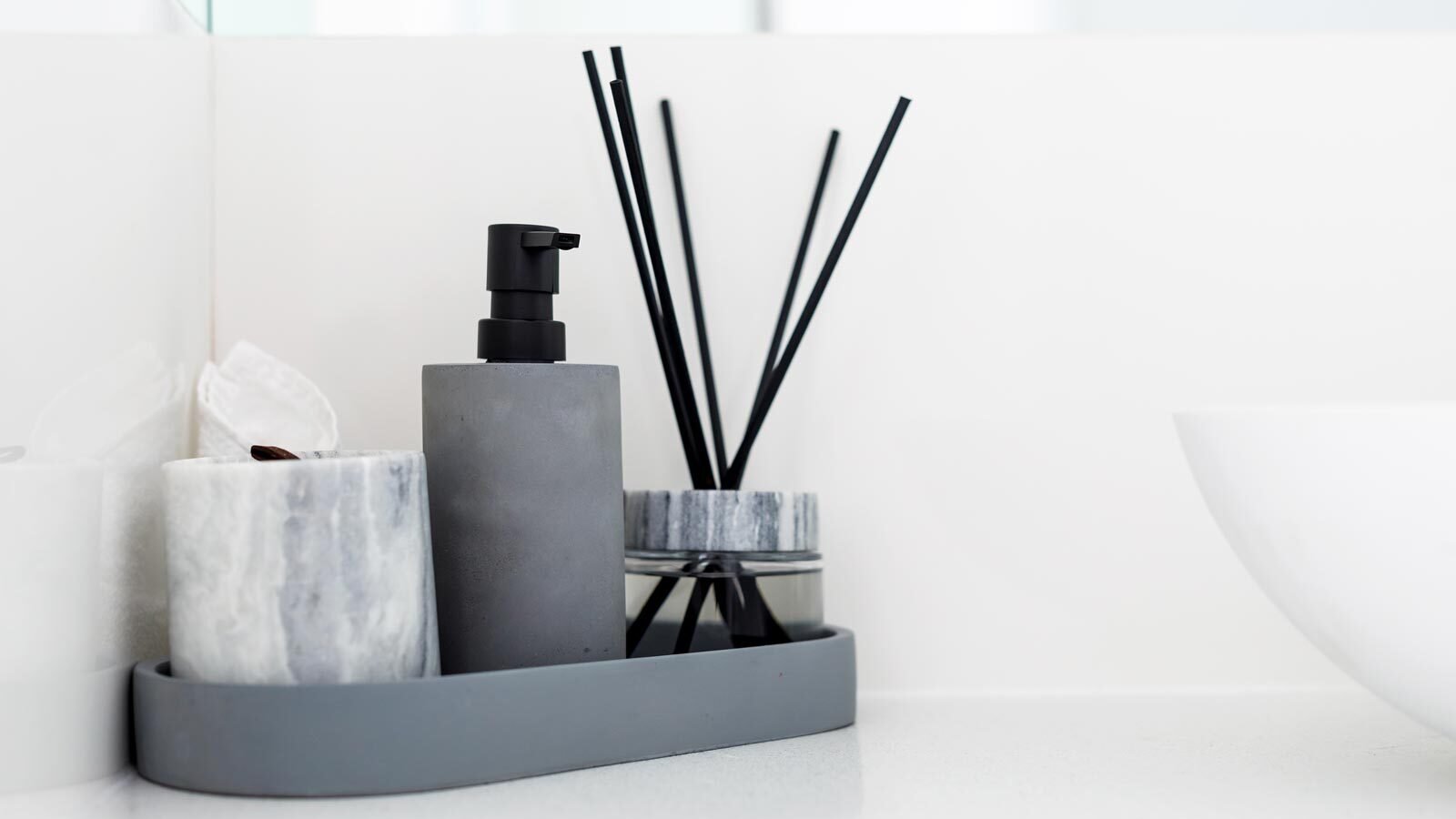 A marble and grey bathroom accessory set featuring a cup, lotion dispenser and oil diffuser