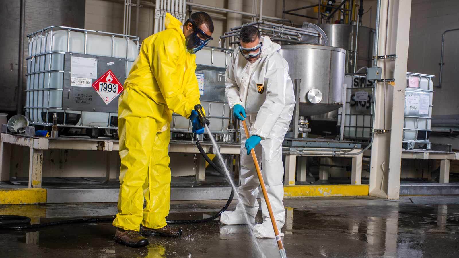 Two men cleaning a floor wearing KleenGuard protective suits