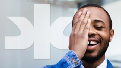 African American man laughing with hand covering right eye and white Kimberly-Clark logo in backgrond