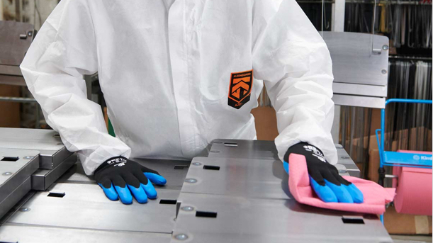 A man wearing KleenGuard apparel, eyewear, and gloves cleaning up using a red wiper