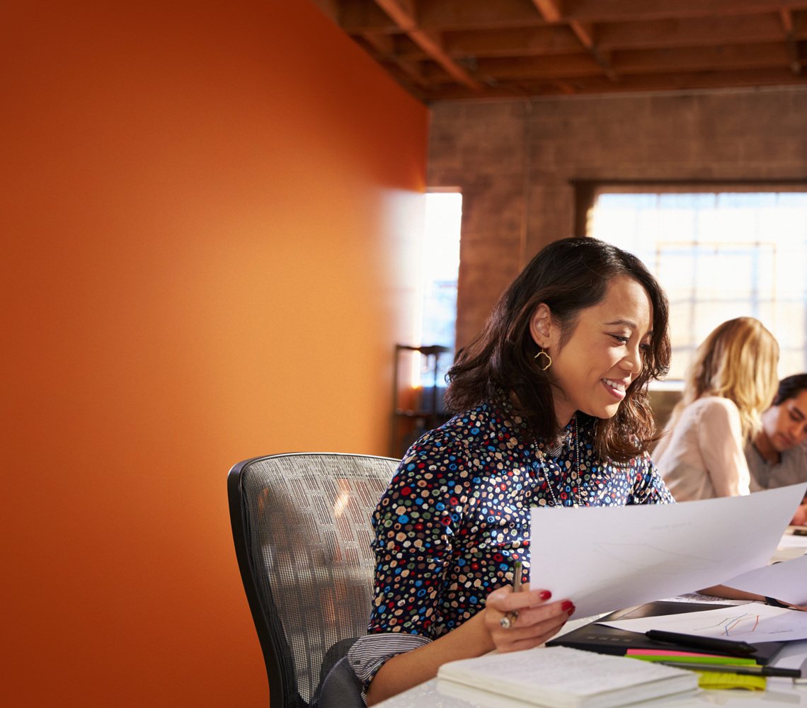 Smiling professional woman sitting at her work desk reviewing documents