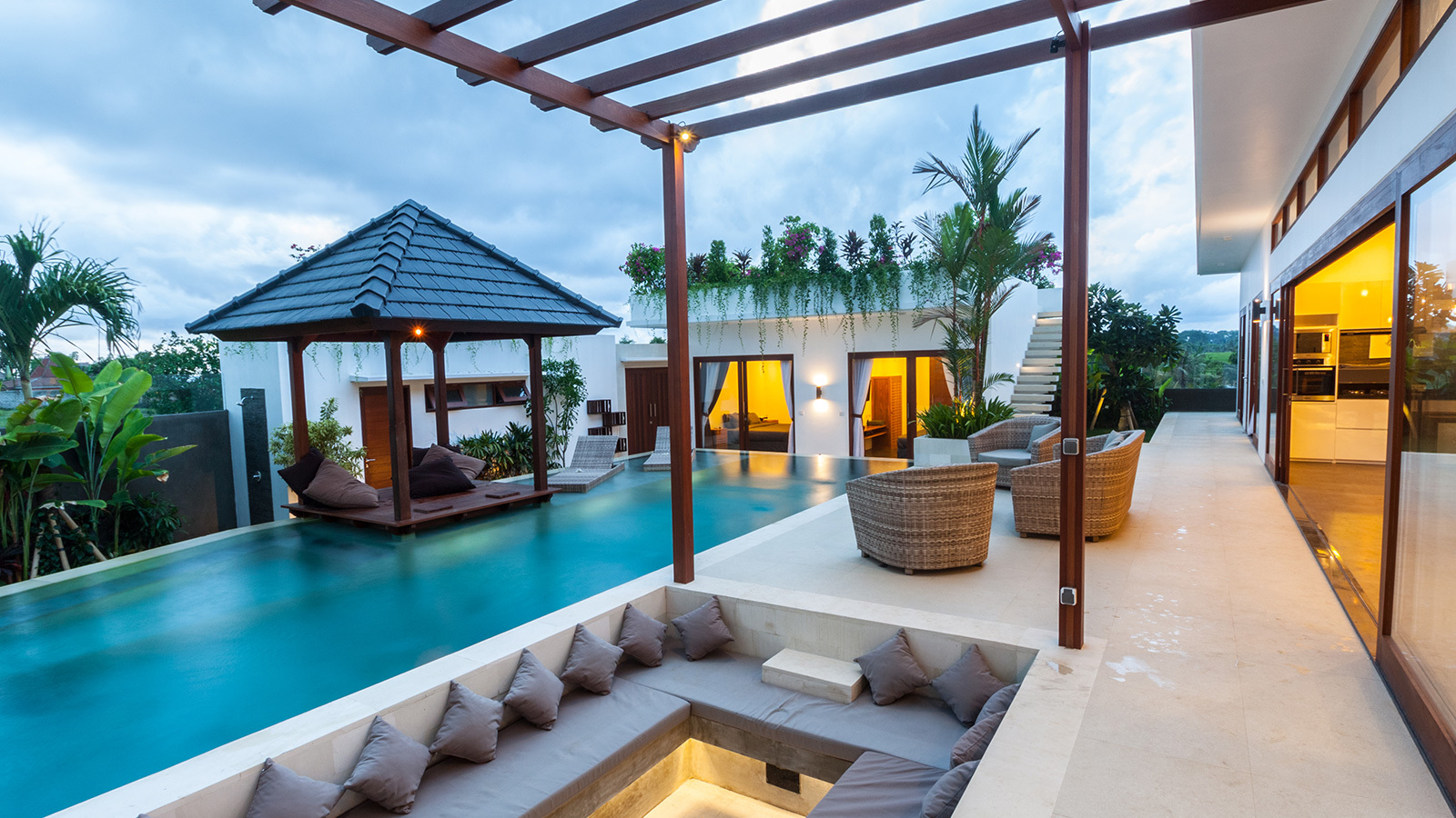 The outside patio of a luxury resort featuring a pool, pergola and outdoor seating