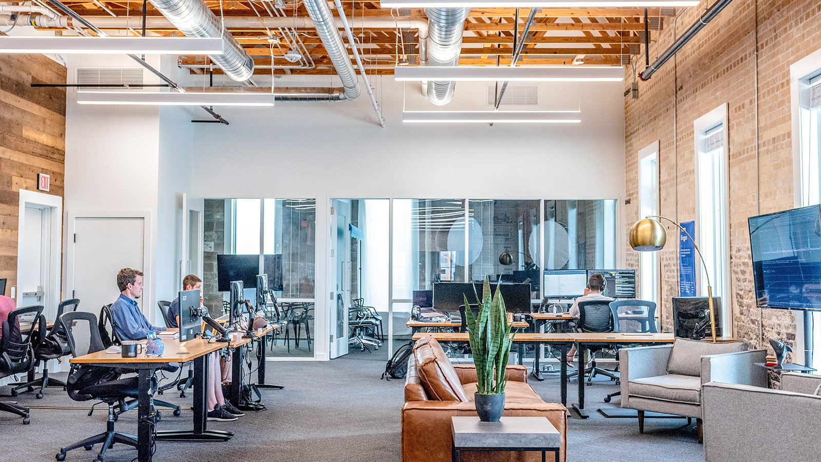 A large office space with several employees sitting at tables and working on computers