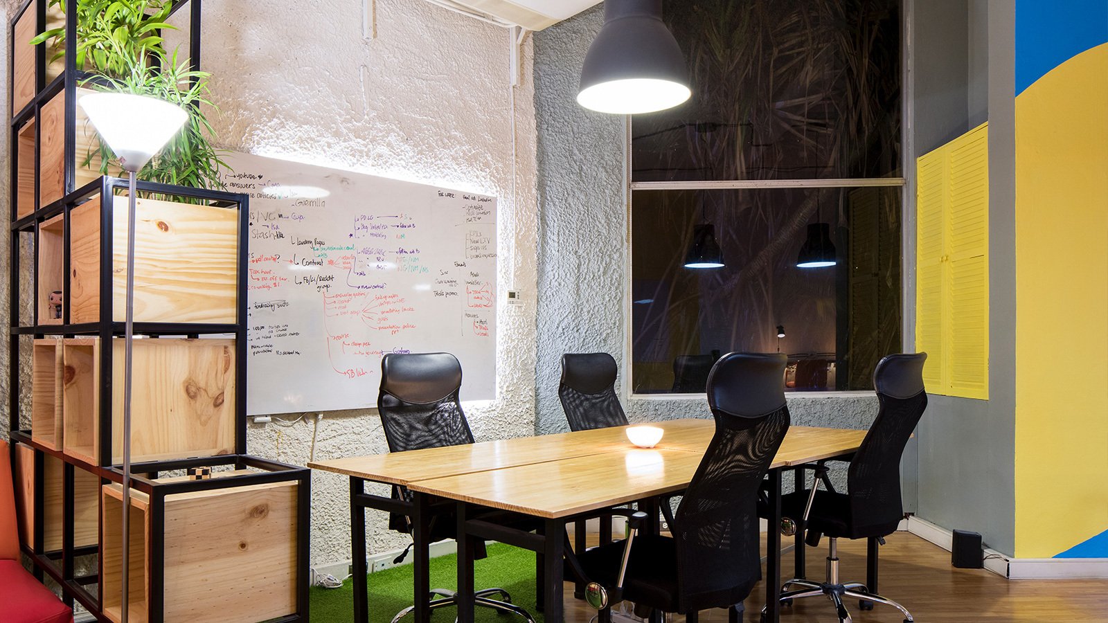 A small office conference room with four black chairs and a table