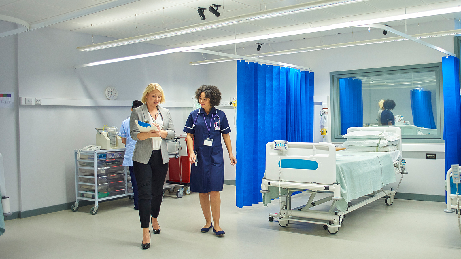 A large hospital room with healthcare professionals and a patient in a hospital bed