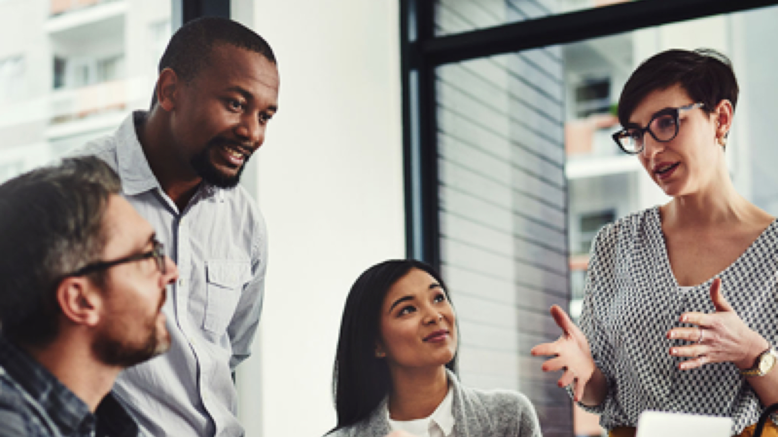 Group of four diverse professional men and women chatting.