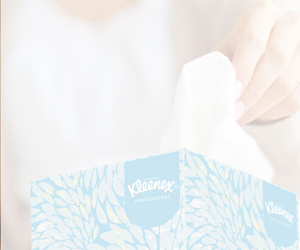 Closeup of a womans hand taking a tissue from a blue decorative box of Kleenex® boutique facial tissues.