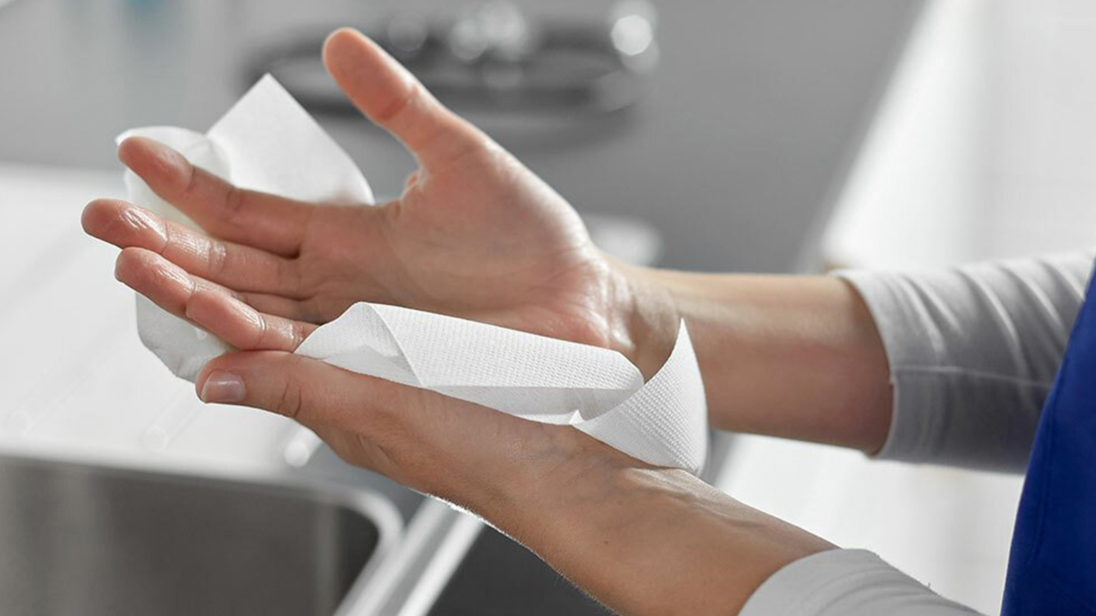 Caucasian drying hands with a white paper hand towel