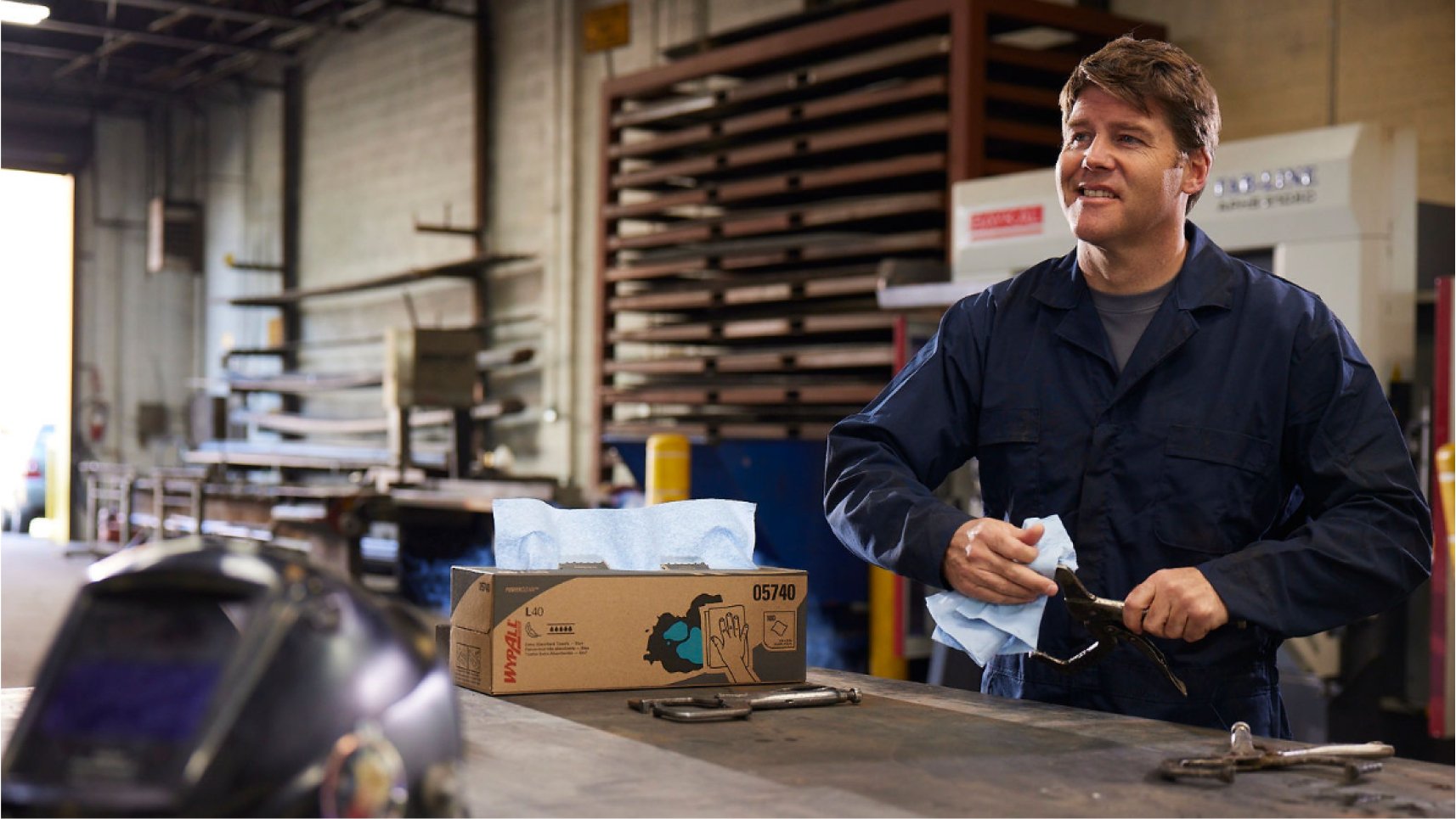 Person in a workshop cleaning tools with WypAll® Wipes.