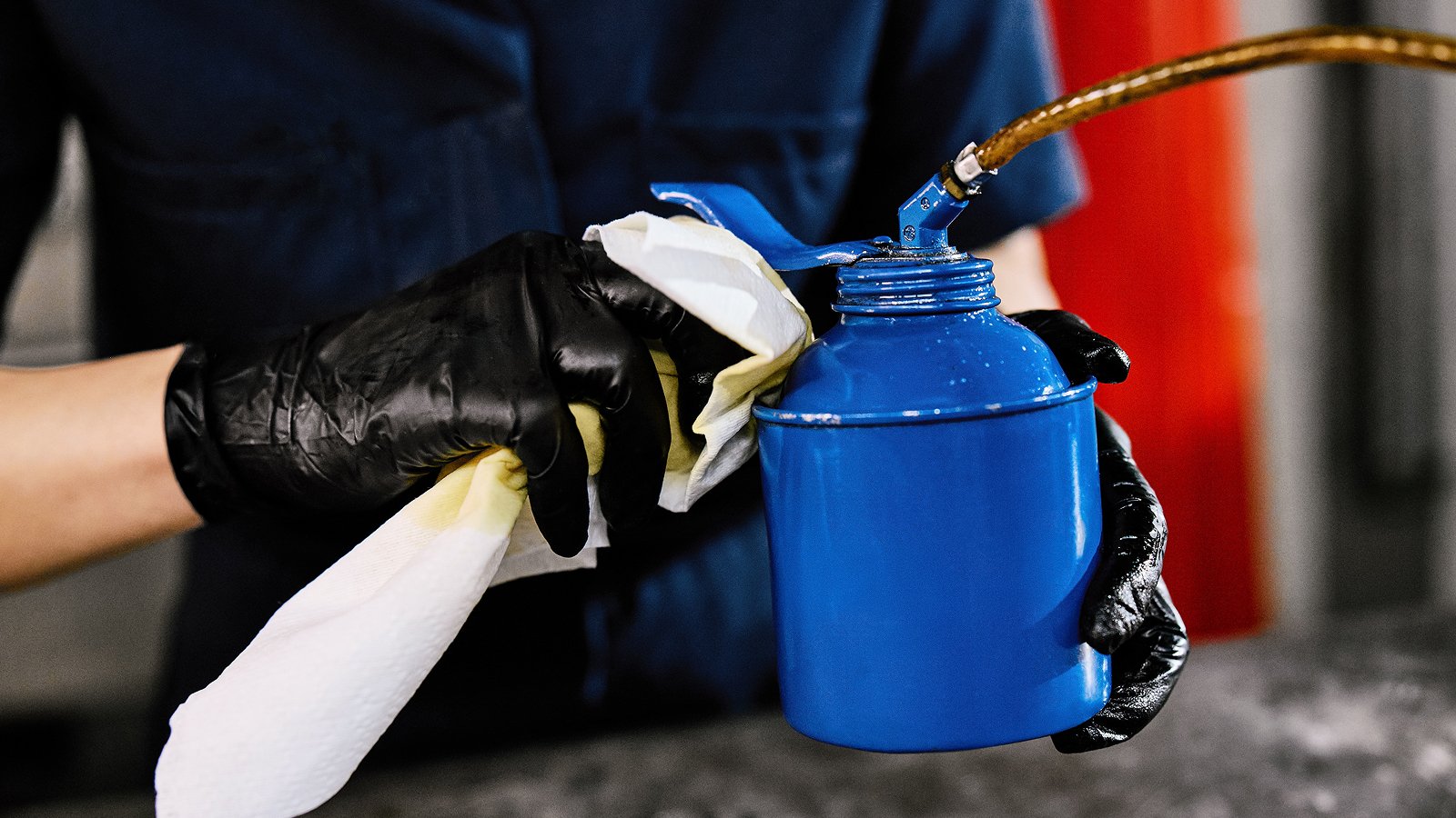 Person holding a blue container and cleaning with a WypAll® X70 medium-duty cleaning cloth. 